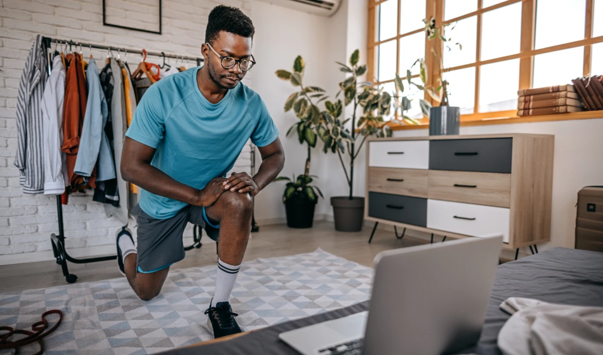 Person doing lunges near laptop